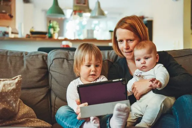 Mama i dzieci, wpatrujący się w tablet. 