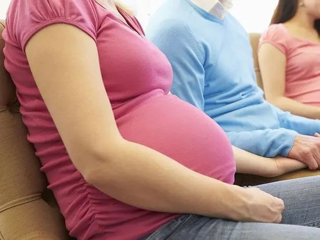 51-latka została surogatką dla swojej córki i jej męża Kobieta w ciąży, trzymająca mężczyznę za rękę.
