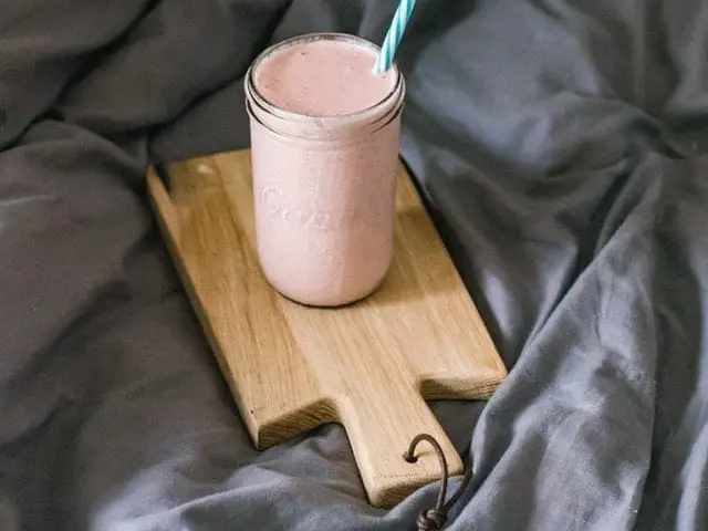 Różowe smoothie na drewnianej desce. 