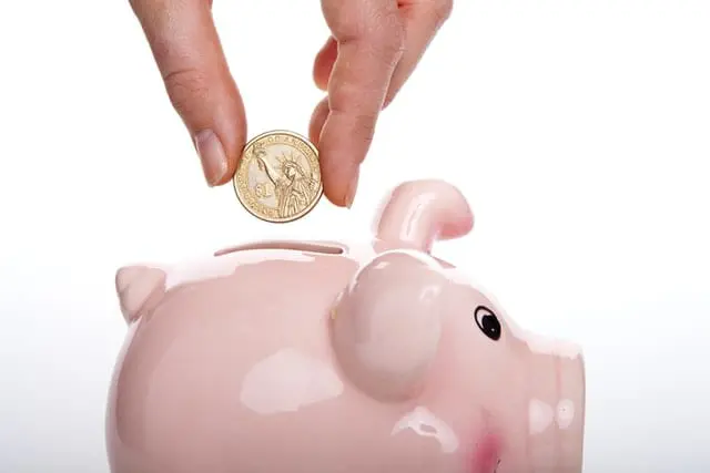5 rad jak oszczędzać pieniądze na co dzień Wrzucanie monety do skarbonki.