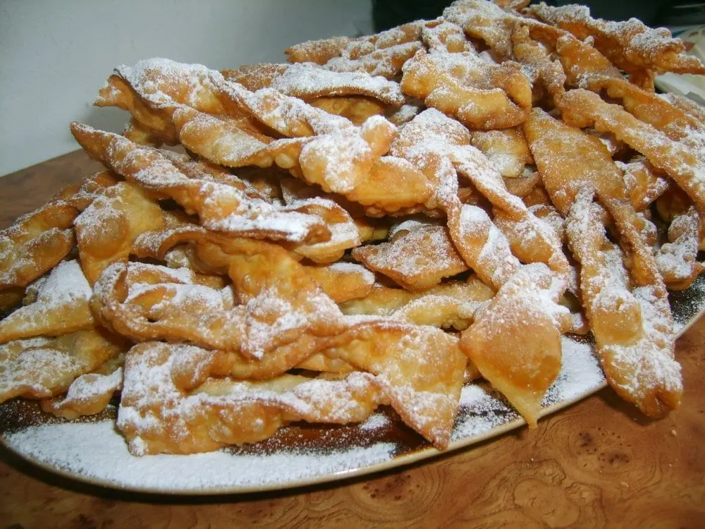 Chrust, posypany cukrem pudrem na talerzu. 