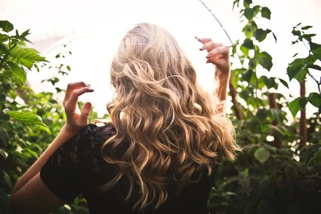 Kobieta z długimi, falowanymi blond włosami pełnymi objętości u nasady
