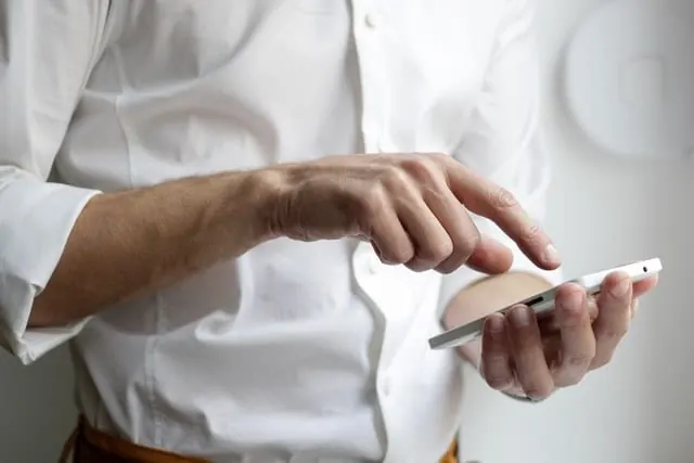 Mężczyzna przegląda telefon, sprawdzanie wiadomości partnera nasila zazdrość w związku