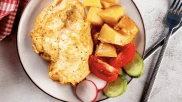 Niesamowicie pyszny i szybki przepis na filet z kurczaka w piekarniku Pieczony filet z kurczaka z ziemniakami, pomidorem i ogórkiem na talerzu