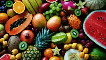 Egzotyczne i sezonowe owoce ułożone na blacie: arbuz, ananas, kiwi, papaja i cytrusy