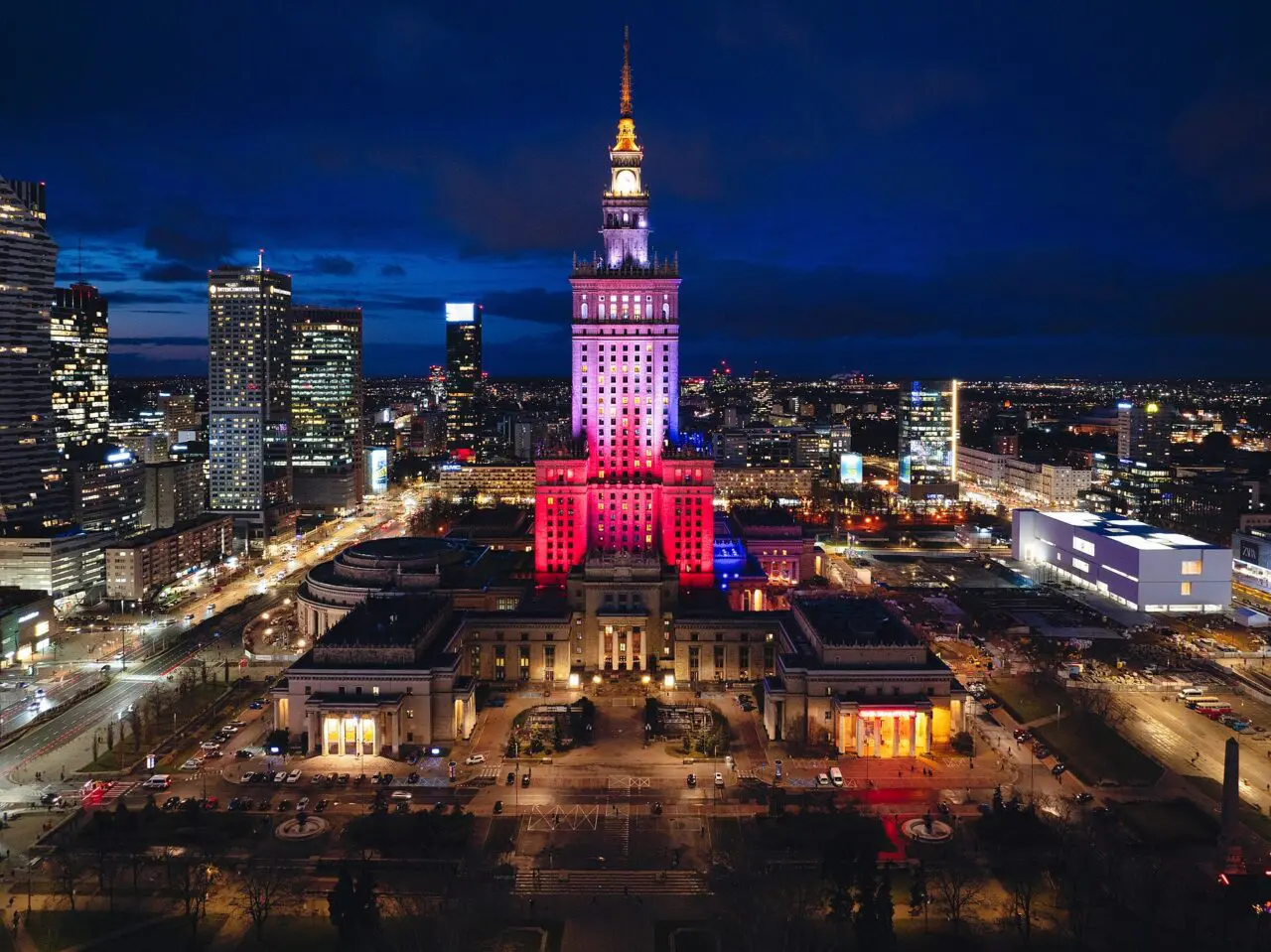 Klimatyczne restauracje Warszawa: miejsca z duszą, ogrodem i tarasem Restauracja z widokiem na Pałac Kultury: podświetlony Pałac Kultury i Nauki nocą na tle wieżowców Warszawy