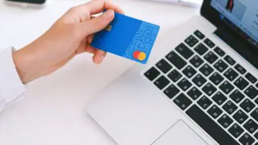 Osoba trzymająca kartę bankową i telefon podczas kontaktu z infolinią Santander