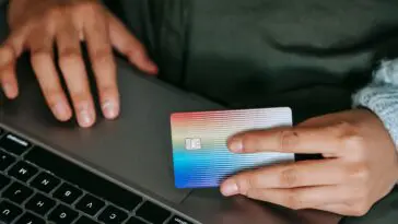 Osoba robiąca zakupy online na laptopie z kartą płatniczą w dłoni