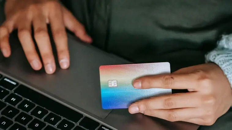 Osoba robiąca zakupy online na laptopie z kartą płatniczą w dłoni