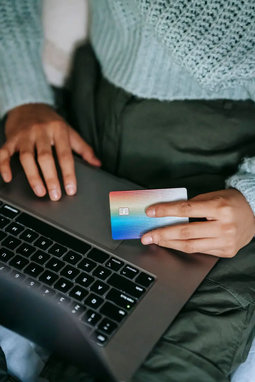 Osoba robiąca zakupy online na laptopie z kartą płatniczą w dłoni