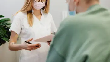 Pracownica rejestracji medycznej przy biurku obsługuje pacjenta infolinii LUX MED