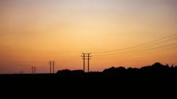 Linie energetyczne i słupy o zachodzie słońca - infolinia PGE
