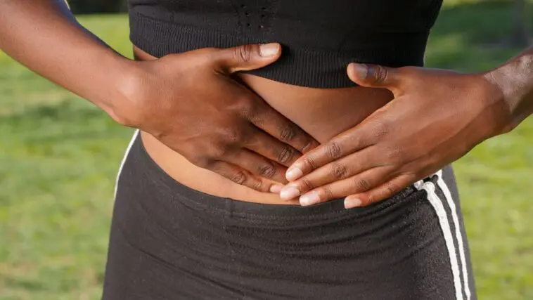 Endometrioza: objawy, przyczyny i leczenie. Choroba, która latami udaje zwykłe bolesne miesiączki Kobieta trzymająca dłonie na podbrzuszu z powodu bólu, ilustracja do artykułu o endometriozie