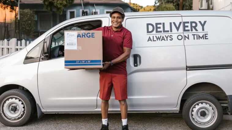 Kurier DHL niosący paczkę do klienta podczas doręczenia