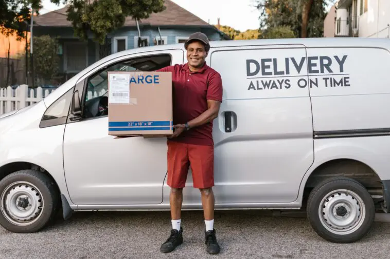 Kurier DHL niosący paczkę do klienta podczas doręczenia