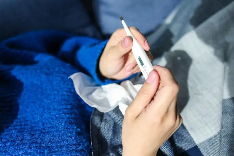 Grypa wariant K (A/H3N2): mylące objawy, które łatwo pomylić z zatruciem. Jak ją rozpoznać i jak się chronić Kobieta z gorączką mierzy temperaturę termometrem, objaw grypy wariant K
