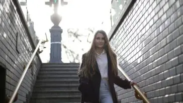 Osoba schodząca po schodach trzymająca się poręczy, profilaktyka upadków w domu
