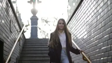 Osoba schodząca po schodach trzymająca się poręczy, profilaktyka upadków w domu