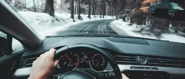 Kierowca trzymający kierownicę podczas jazdy samochodem po drodze