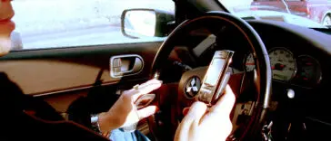 Kierowca trzymający telefon komórkowy w dłoni podczas jazdy samochodem