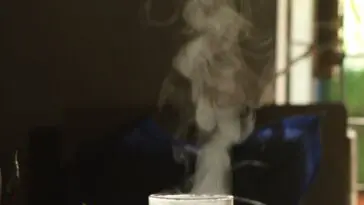 Szklany czajnik z parującą, gotującą się wodą przy oknie