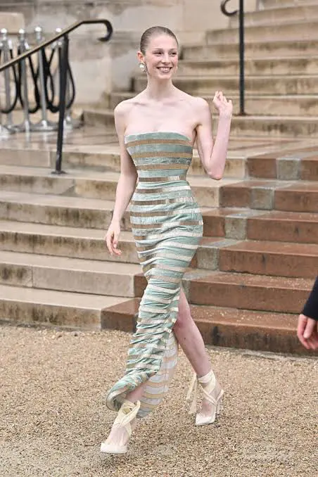 Hunter Schafer na pokazie mody Hunter Schafer w srebrnej sukience na schodach podczas pokazu mody