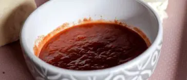 Miska sosu pomidorowego obok świeżych pomidorów i mozzarelli