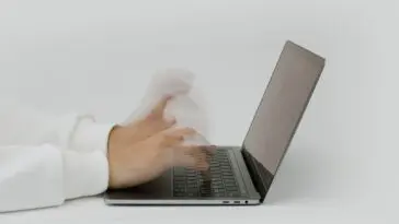 Dłonie wpisujące hasło na klawiaturze laptopa