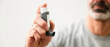 Mężczyzna korzystający z inhalatora, objawy POChP i trudności w oddychaniu