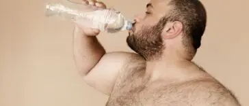 Mężczyzna pije wodę z plastikowej butelki