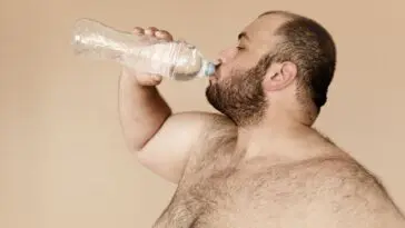 Mężczyzna pije wodę z plastikowej butelki
