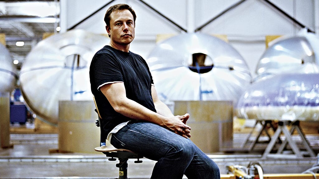 Elon Musk, siedzący na krześle. 