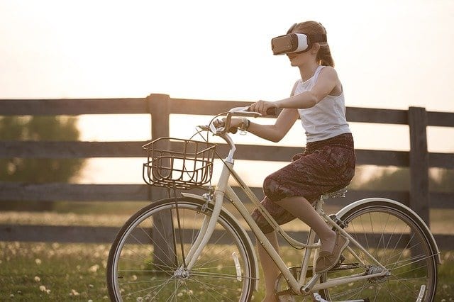 Dziewczynka jadąca na rowerze w okularach VR. 