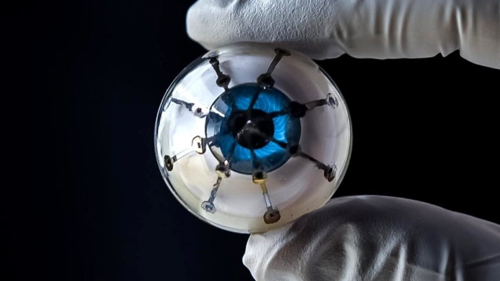 Prototyp bionicznego oka trzymany w palcach. 