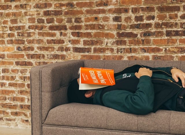 Mężczyzna śpiący z książką na głowie. 