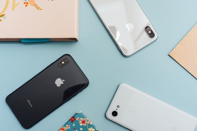 Trzy iPhony znajdujące się obok siebie na błękitnym tle. 