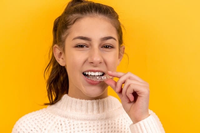 Dziewczyna wyjmująca aparat na zęby z ust.