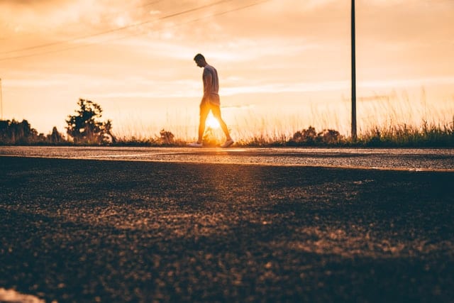 Mężczyzna podążający drogą na tle promieni słońca. 