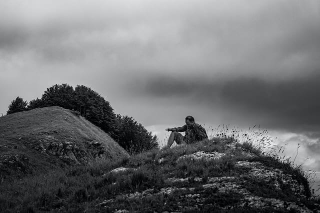 Mężczyzna siedzący w górach - czarnobiałe zdjęcie. 