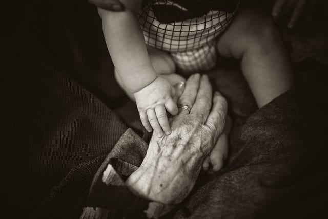 Dłoń starszej osoby i dłoń dziecka.