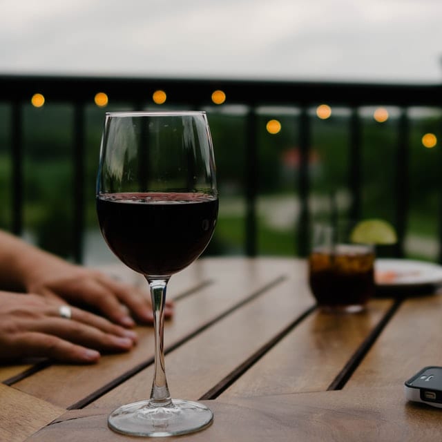 Sztuczki fotografów reklamowych Wino w kieliszku na drewnianym stoliku.