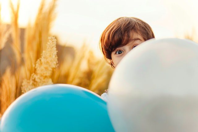 Chłopiec patrzący z za balonów.