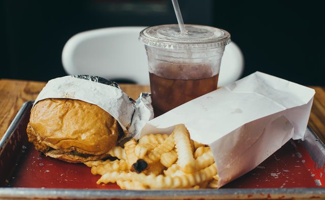 Burger, frytki i cola na tacce. 