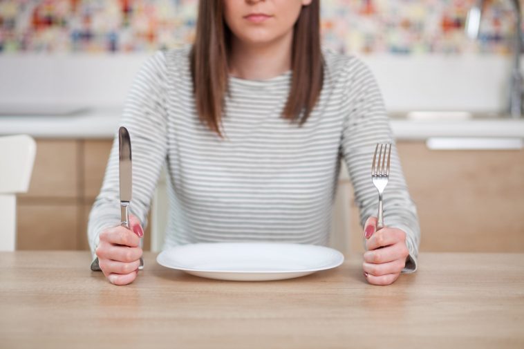 Kobieta siedząca przy pustym talerze.