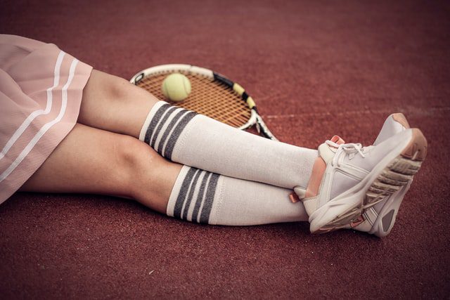 Czy uprawianie sportu może szkodzić Kobieta leżąca na korcie tenisowym.