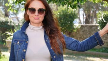 Kobieta w okularach przeciwsłonecznych i kurtce jeansowej w słoneczny jesienny dzień
