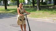 Osoba jadąca hulajnogą elektryczną po miejskiej ulicy