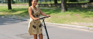 Osoba jadąca hulajnogą elektryczną po miejskiej ulicy