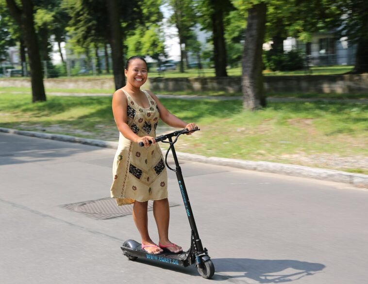 Osoba jadąca hulajnogą elektryczną po miejskiej ulicy