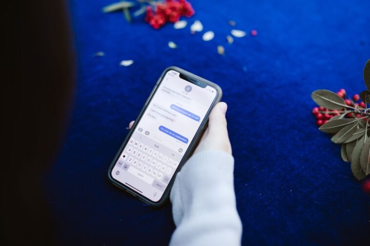 SMS o dopłacie 3 zł, który kosztuje dorobek życia. Tak dziś działają oszuści Dłoń trzymająca smartfon z otwartą wiadomością SMS